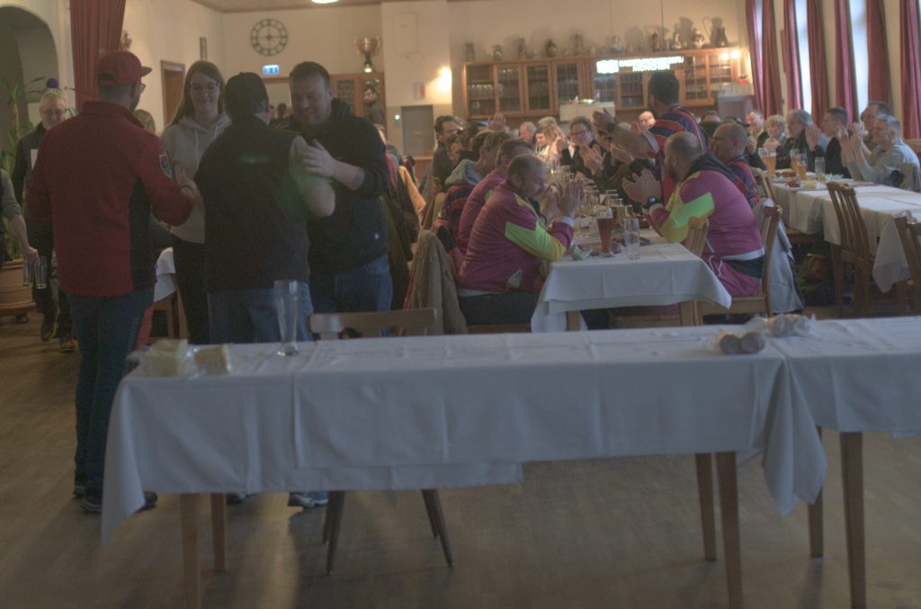 Bild zeigt die Preisübergabe bei der Siegerehrung im Saal des Gasthofs. Die Mannschaft ist nicht bekannt. Es sind jeweils die 4 Teilnehmer der jeweiligen Mannschaft zu sehen.