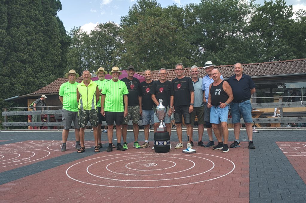 Siegerfoto mit den ersten drei Mannschaften, in der Mitte der Pokal am Boden stehend auf einem 30 Liter Bierfass.